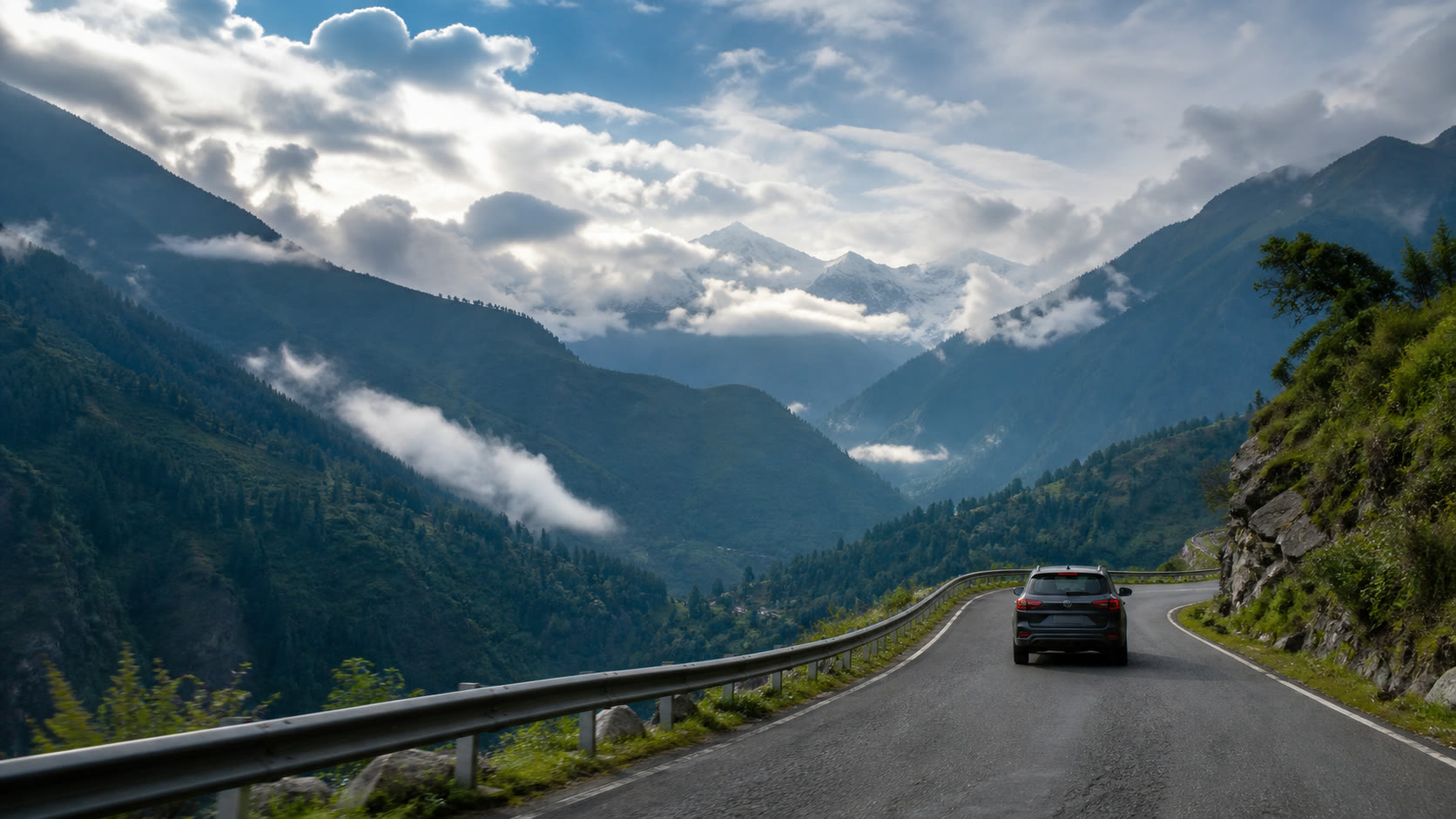 A graphite SUV following a mountain road through the Himalayas